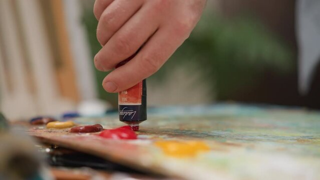 Artist squeezes paint onto palette in studio