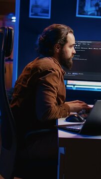 Developer pressed by deadline, drinking coffee and doing multitasking to finish developing PC code. Caffeinated IT specialist solving database error using multiple desktop and laptop screens, camera B