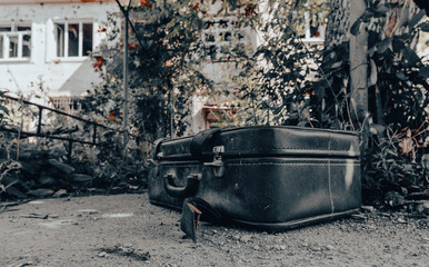 old suitcase against the background of a destroyed house in an abandoned city in Ukraine