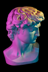 Gypsum copy of head statue David in bright neon colors for artists isolated on a black background....