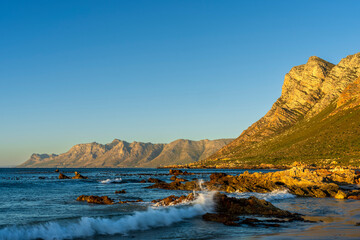 Evening views towards Gordons Bay and the Kogelberg Mountains across False Bay from Rooi-Els beach near Cape Town, Western Cape. South Africa.