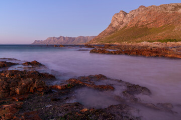 Evening views towards Gordons Bay and the Kogelberg Mountains across False Bay from Rooi-Els beach near Cape Town, Western Cape. South Africa.