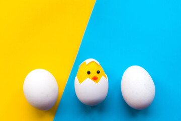 Toy chicken and eggs on bright blue and yellow background. Copy space for the text. Easter concept
