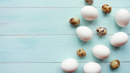 Chicken and quail eggs on wooden background. Easter concept.