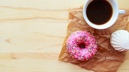 White zefir, coffee cup and pink donut on wooden table, top view. Copy space for the text