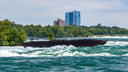 Fototapeta na wymiar Old rusty iron barge stuck on rocks in a lake near Niagara Falls, Niagara State Park, USA
