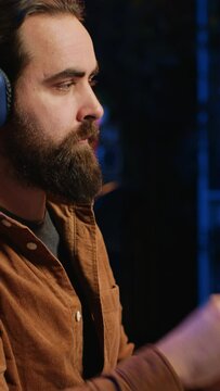 Smiling developer listening music while doing programming during remote job shift in home office. Upbeat IT admin enjoying audio podcast, working on PC in apartment late at night, close up