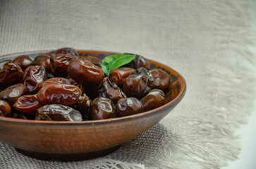 Dates in a brown plate on a textured light background, side view