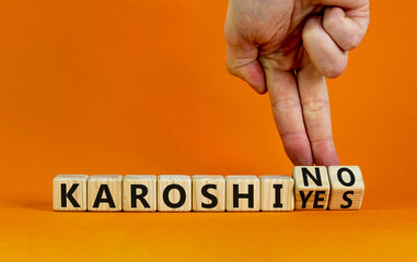 Karoshi yes or no symbol. Concept words Karoshi Yes or No on beautiful wooden blocks. Beautiful orange table orange background. Businessman hand. Business and stop karoshi concept. Copy space.