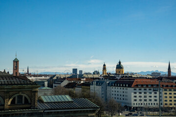 Fototapeta na wymiar Munich skyline. View from the Technical University Munich, Germany. St. Markus on the left, the domes of the Theatiner Church on the right. In the background the silhouette of the Alps. Blue sky
