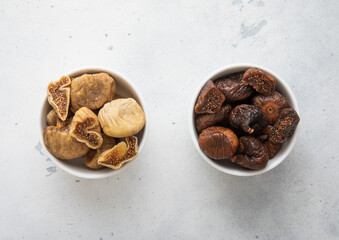 Two kitchen bowl plates with white and brown organic dried organic figs on light background.Top view.