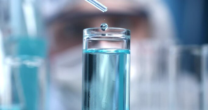 Super slow motion close up of scientist examines with pipette molecules of DNA sample substance in test tubes during biochemical analysis of experimental data research in laboratory at 1000 fps.