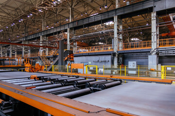 Steel sheet moving on roller conveyor in metalworking workshop