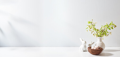 Spring flowers in a vase and easter bunny on a white table. Easter background with copy space