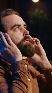 Cheerful programmer listening music while doing web development during remote job shift in neon lit home office, finishing coding project. IT expert enjoying audio podcast, working on PC, camera A