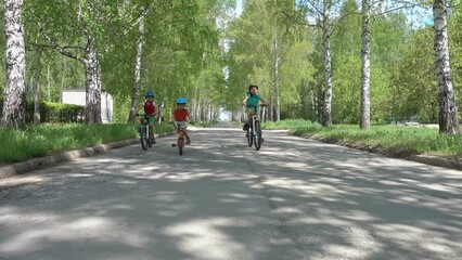 Cheerful childrens-cyclist riding bicycle outdoor during daylight. Kids riding bicycles in the street. Family enjoying a bike trip. Boys in safety helmets riding bike.