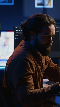Computer scientist putting headphones on while developing code on PC, making time pass faster during remote job shift. IT admin doing multitasking in home office while listening music, camera A