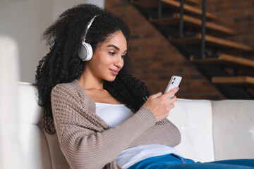 Side view portrait of young cheerful african woman listening to the music radio podcast, choosing...