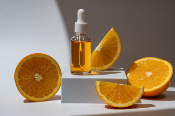 Glass bottle with an orange oil dropper for skin, hair. Packaging with serum on white background in rays of sunlight. Container with cosmetics for skin care on a podium. Concept of mockup, branding.