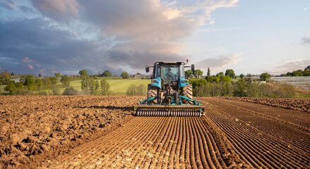 Agriculteur au volant de son tracteur labourant les champs au printemps dans un paysage de campagne en France. © Thierry RYO