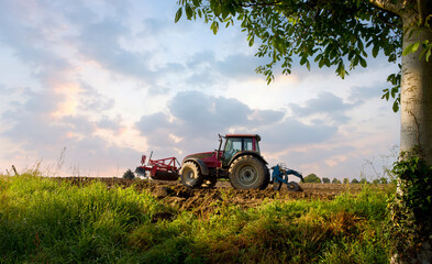 Agriculteur au volant de son tracteur labourant les champs au printemps dans un paysage de campagne...