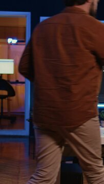 Developer arriving in apartment office with coffee mug in hand, ready to start coding on computer. IT specialist begins teleworking job shift, holding cup of tea, upgrading company software, camera B