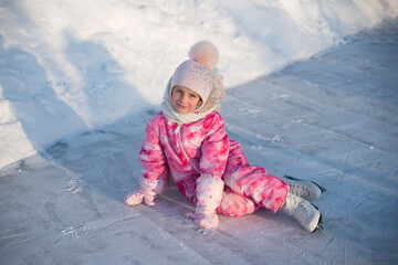 girl in pink overalls and pink hat skating on street rink