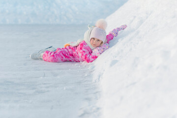 girl in pink overalls and pink hat skating on street rink