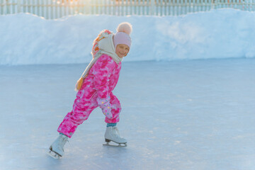 girl in pink overalls and pink hat skating on street rink