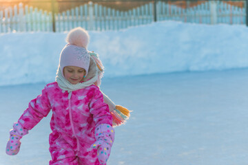 girl in pink overalls and pink hat skating on street rink