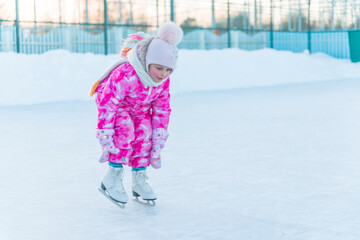  girl 5 years old rides white figure skates in winter at the ice rink.