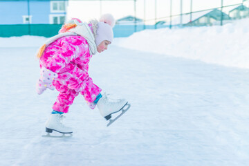 girl in pink overalls and pink hat skating on street rink