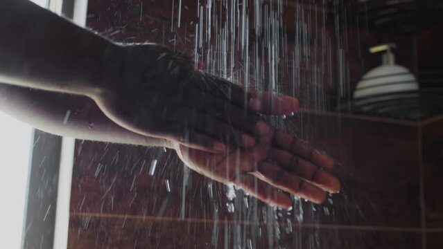 Close-up slowmo shot of hands of anonymous African American or Asian man turning shower faucet handle and washing under running water during morning personal care routine