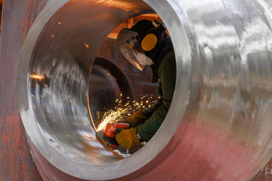 A worker processes nozzle of the reactor vessel with special equipment.