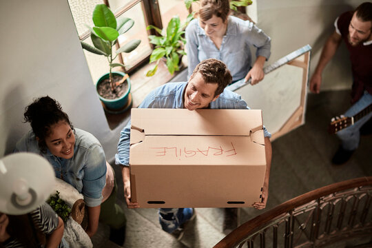 Diverse group of young people moving in their new shared apartment and carrying boxes