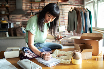 Asian Woman Packing Clothes at Home Business