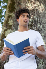 young man reading a book in the park