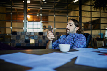 Young businessman using smartphone in modern office