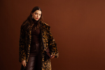 Fashionable confident woman wearing trendy faux fur leopard print coat, turtleneck, leather pants,...