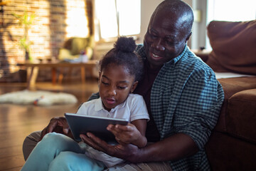 Happy father and daughter with tablet at home