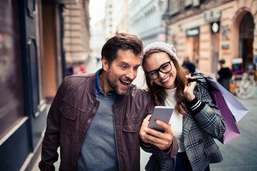 Couple shopping and looking at phone in city street