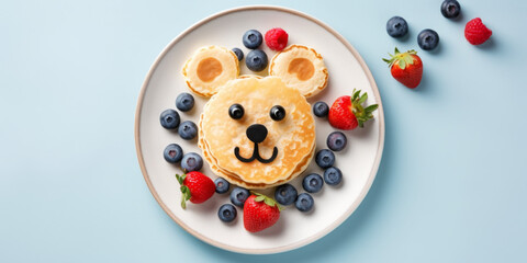 Pancake Shaped like a Bear Surrounded by Fresh Berries on a Pastel Blue Background