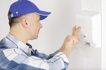 worker screwing a detector to the wall