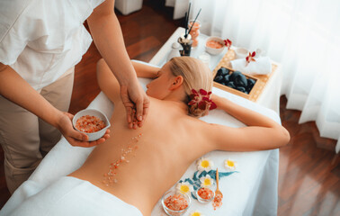 Woman customer having exfoliation treatment in luxury spa salon with warmth candle light ambient....