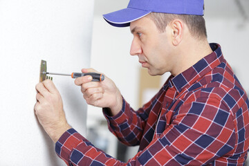 male handyman screwing a bracket onto the wall