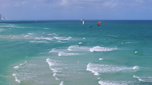 Vibrant and active seascape with kitesurfing amidst turquoise waters and white waves. Clear sky and lively atmosphere. Resting and relax outdoors