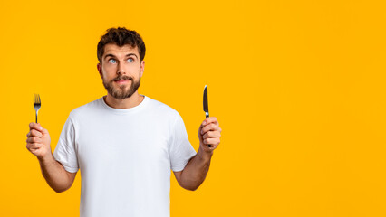 Hungry guy holds knife and fork ready savor meal, studio