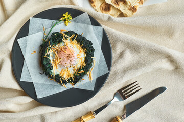 Easter breakfast idea. Baked spinach egg nests decorated with grated cheese and black pepper. Festive meals. Funny healthy food for kids.
