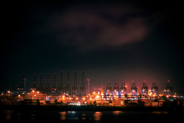 Fototapeta na wymiar Night in the harbor of Hamburg with cranes and clouds and lights