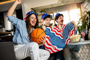 Latino family is watching basketball match with American flag.